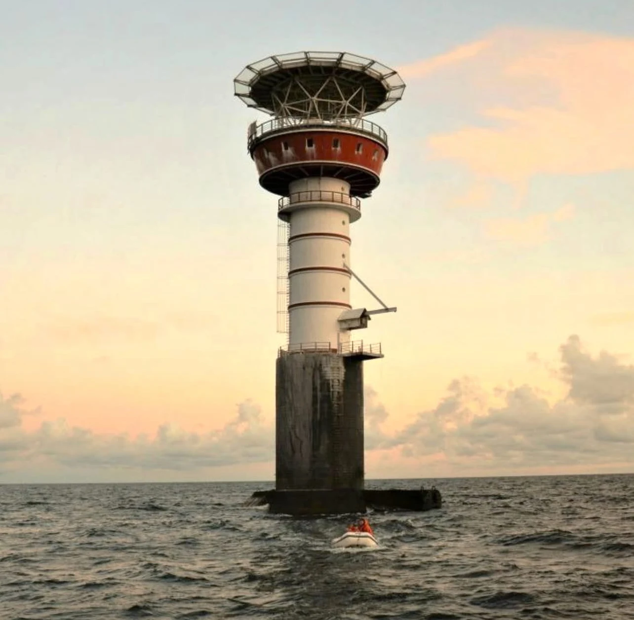 The Irbe lighthouse standing alone in the Baltic Sea at sunset